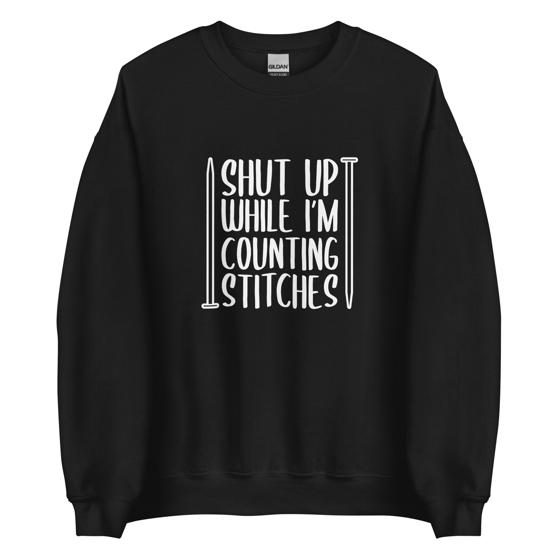 A black crewneck sweatshirt with white text surrounded by two knitting needles. The text reads "Shut up while I'm counting stiches".