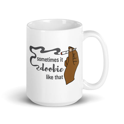 A white 15 ounce ceramic coffee cup featuring an illustration of a hand with deep brown skin holding a joint. Text alongside the hand reads "sometimes it doobie like that" with the word "doobie" made from smoke from the joint.