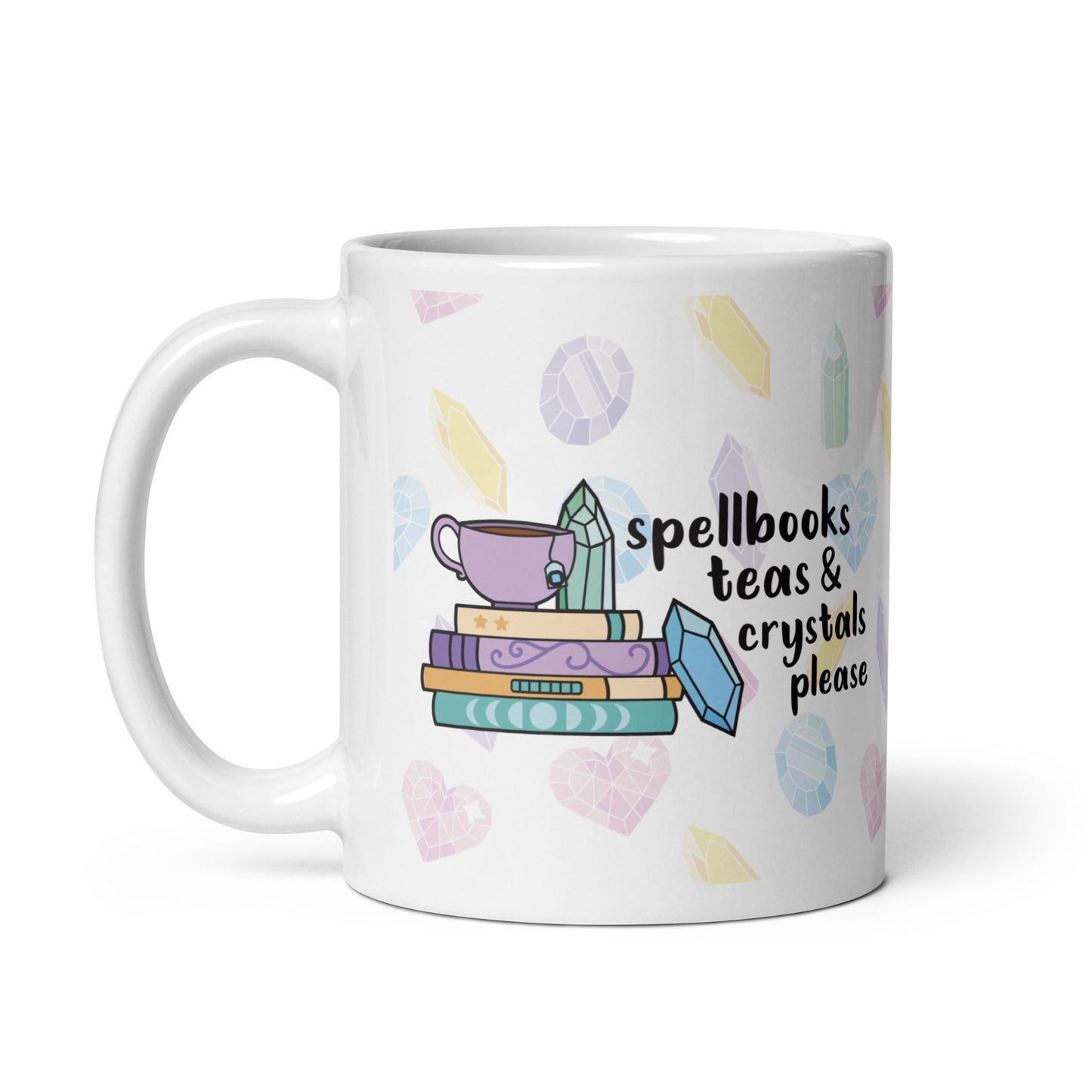 A white 11 ounce ceramic mug with a pattern of pastel crystals. In the center of the mug is an illustration of several books and crystals and a teacup. Text along side the image reads "Spellbooks, teas, & crystals please"