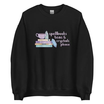 A black crewneck sweatshirt featuring an illustration of a stack of spellbooks with a teacup and a crystal resting on top. Another crystal rests on the side of the stack, and text next to the illustration reads "Spellbooks, teas & crystals please"