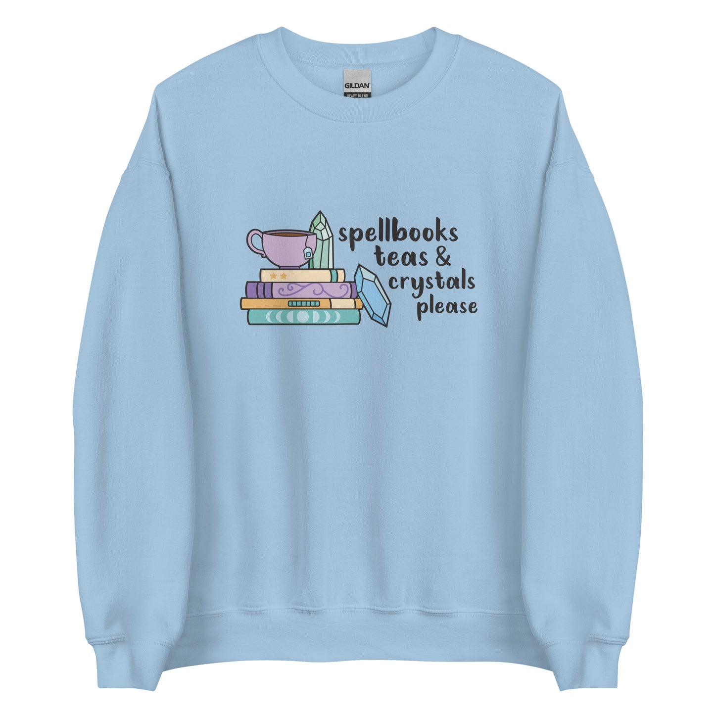 A light blue crewneck sweatshirt featuring an illustration of a stack of spellbooks with a teacup and a crystal resting on top. Another crystal rests on the side of the stack, and text next to the illustration reads "Spellbooks, teas & crystals please"