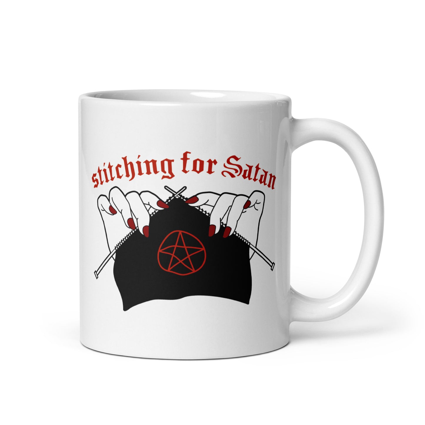A white 11oz ceramic coffee mug featuring an illustration of pale white hands with red fingernails holding knitting needles. Fabric on the needles features a red pentagram. Text above the hands reads "stitching for Satan" in a gothc red font.