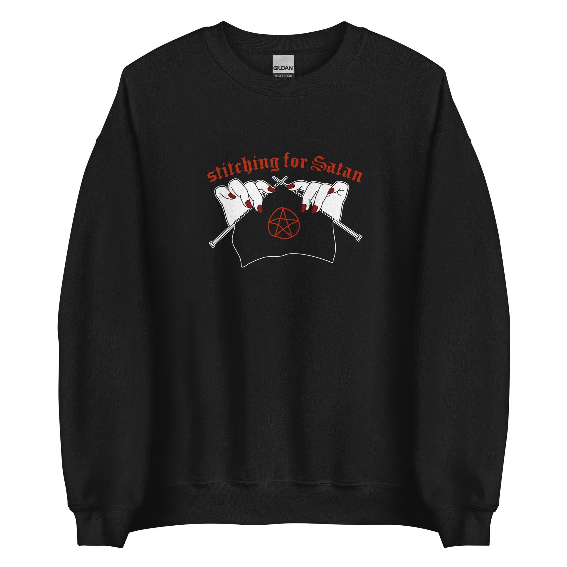 A black crewneck sweatshirt featuring an illustration of pale white hands with red fingernails holding knitting needles. Fabric on the needles features a red pentagram. Text above the hands reads "stitching for Satan" in a gothc red font.