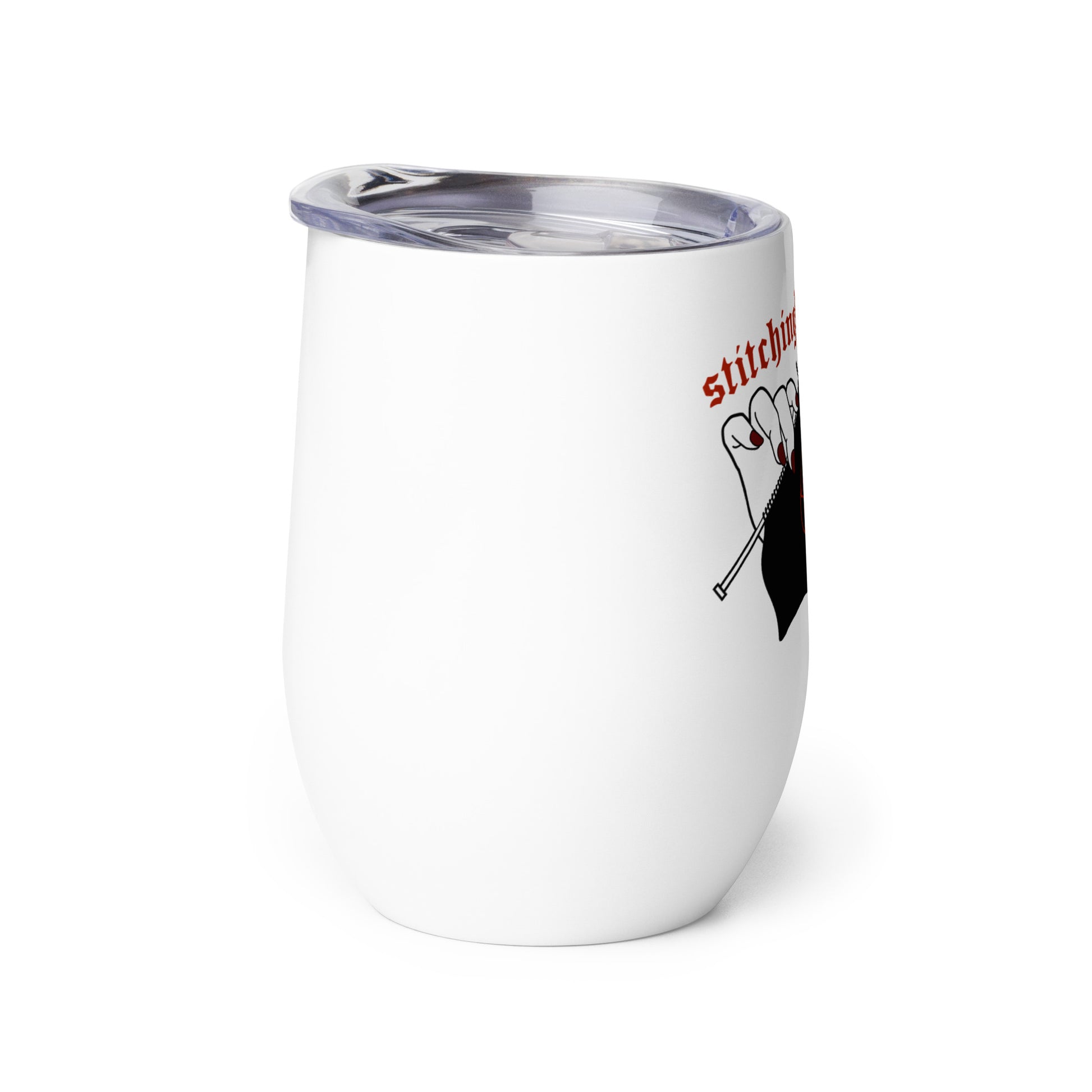 A side view of a white 12 ounce wine tumbler with a clear plastic lid. One side of the tumbler is decorated with an illustration of pale white hands with painted red nails holding knitting needles. Black fabric on the needles features a red pentagram, and text above the hands reads "stitching for Satan" in a gothic red font.