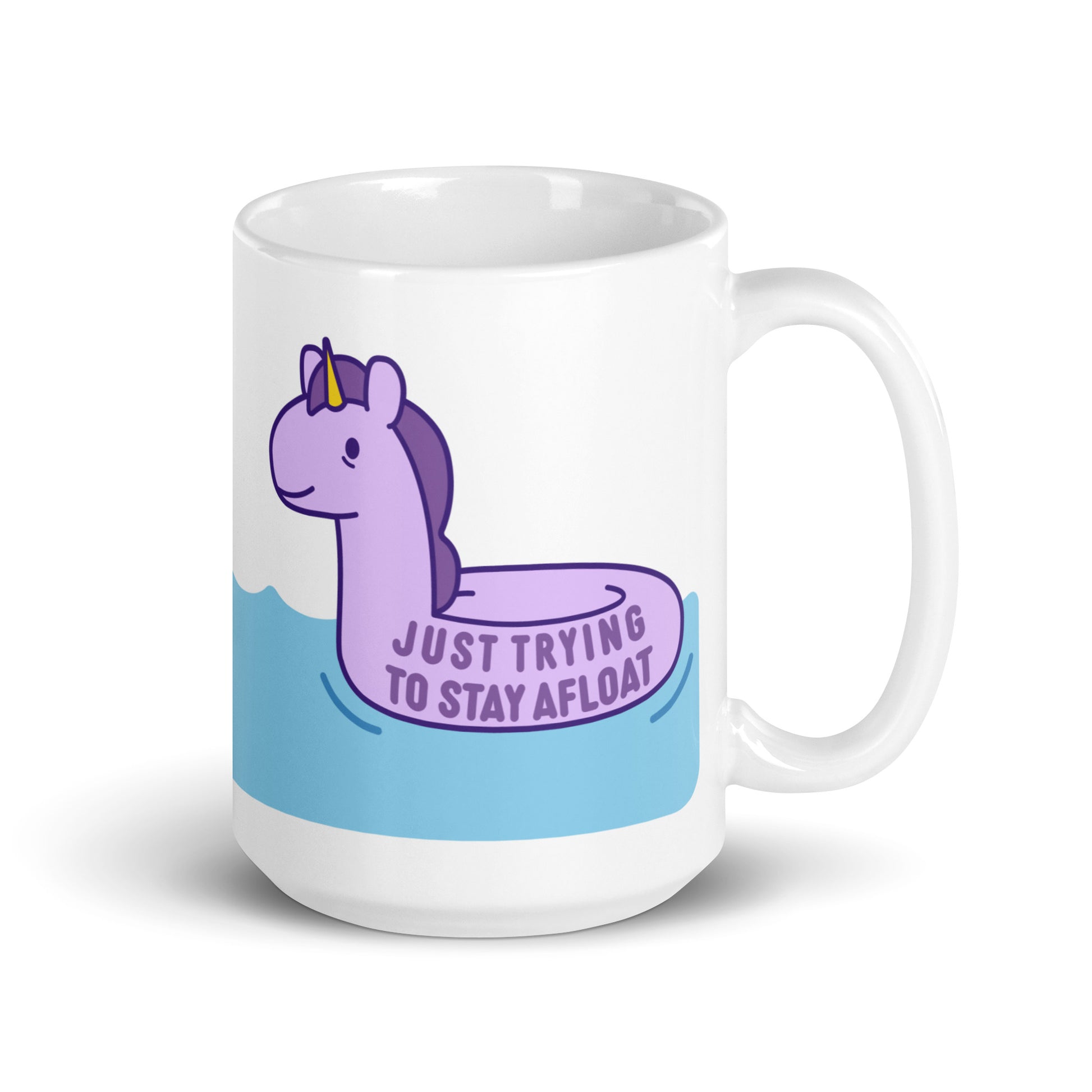 A white 15oz ceramic mug with a purple unicorn pool float floating on water and text reading "Just trying to stay afloat"