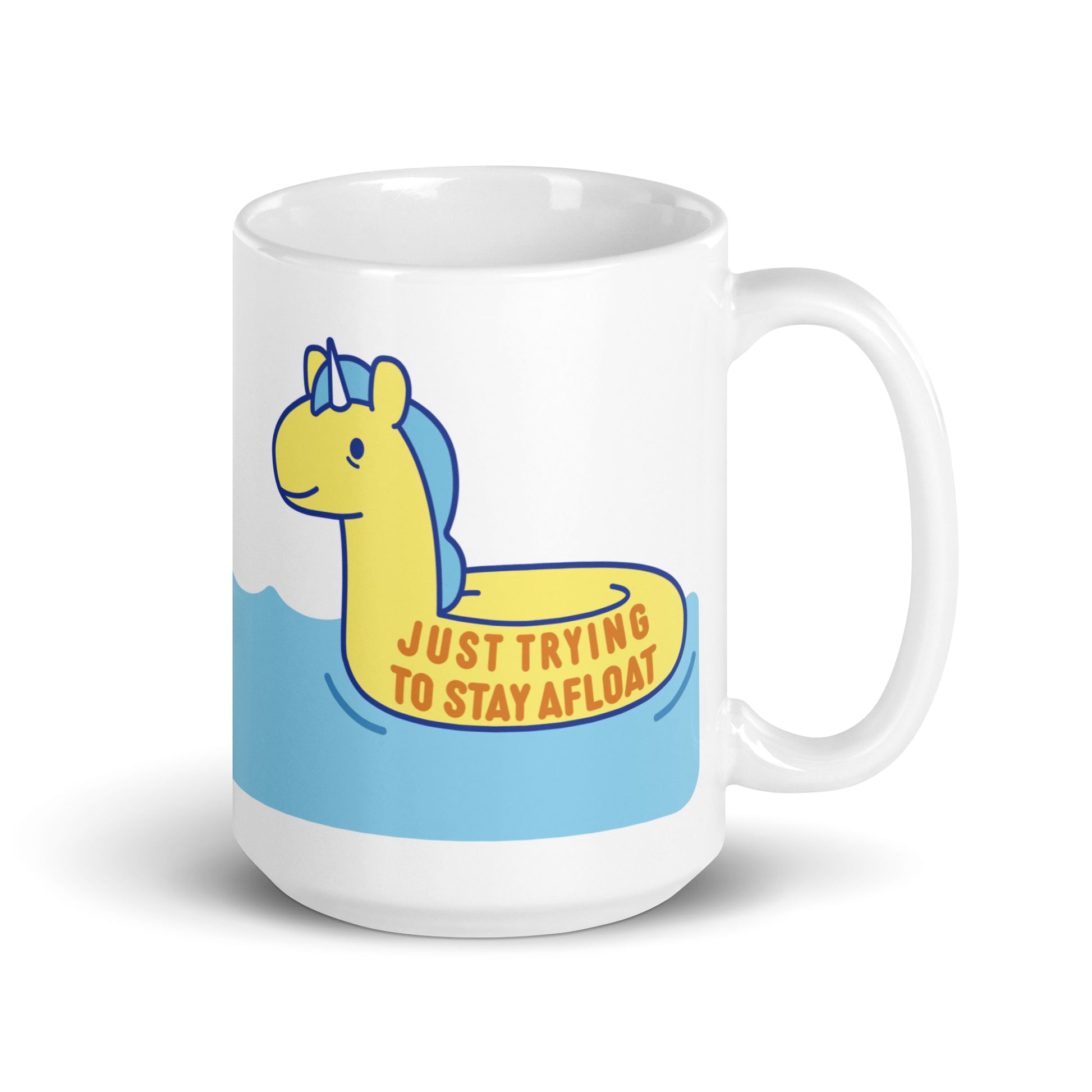 A white 15oz ceramic mug with a yellow unicorn pool float floating on water and text reading "Just trying to stay afloat"