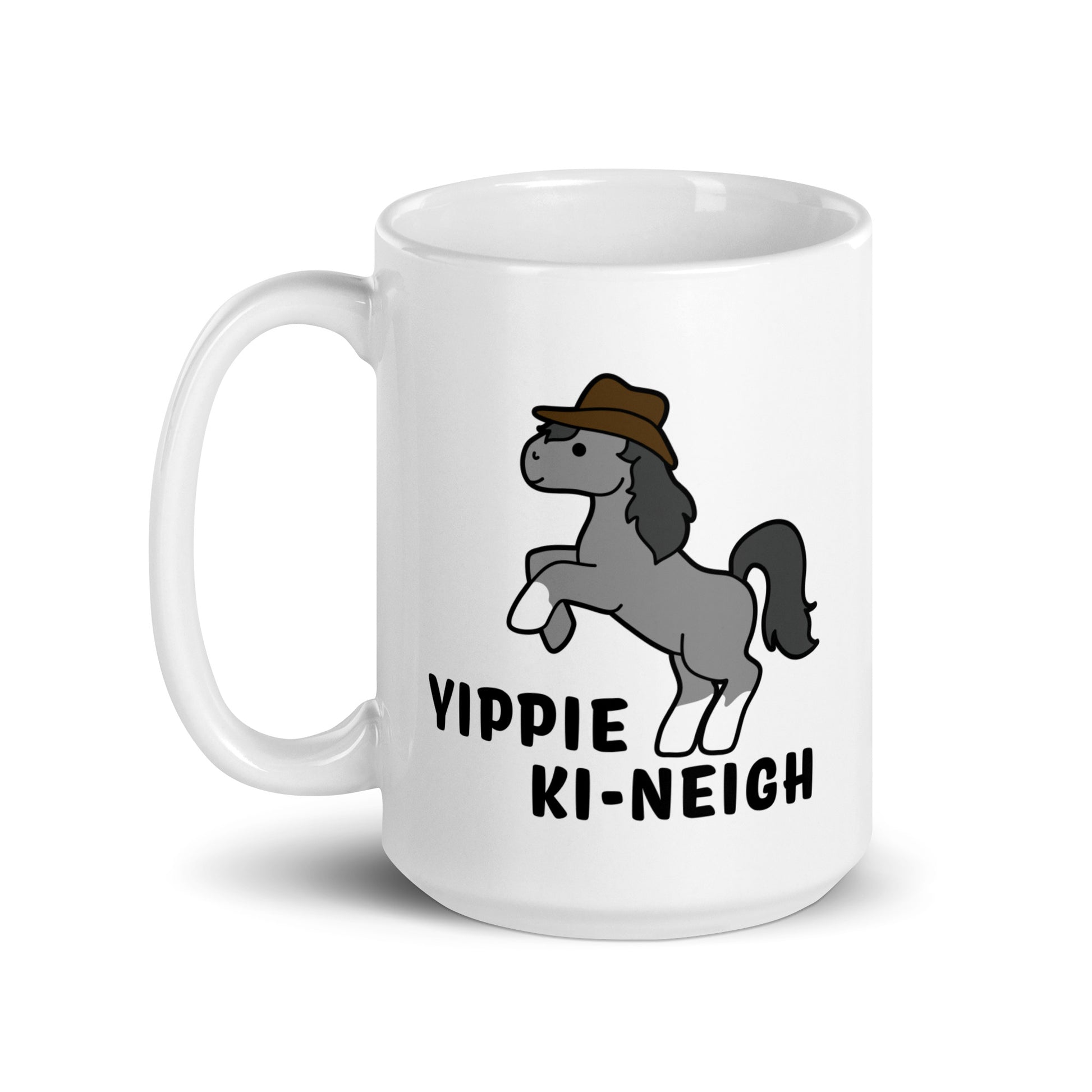A white 15 ounce ceramic coffee mug featuring an illustration of a smiling grey pony rearing and wearing a cowboy hat. Text underneath the pony reads "Yippie Ki-Neigh"